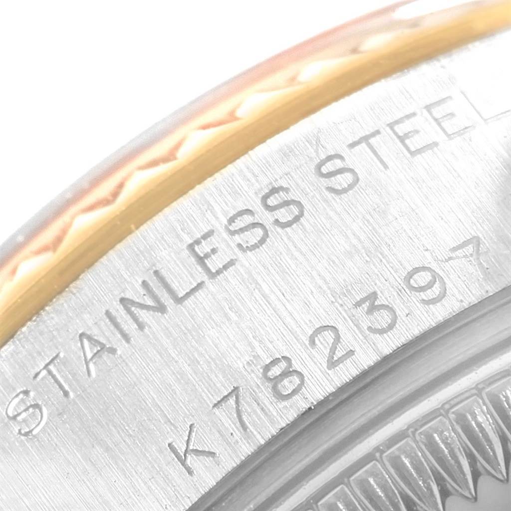 The image shows a close-up of the Rolex Datejust 79173 Women's Steel and Gold (two tone) White Dial 79173 Women's Steel and Gold (two tone) White Dial watch bezel and part of the stainless steel case, showcasing engraved text and watch details.