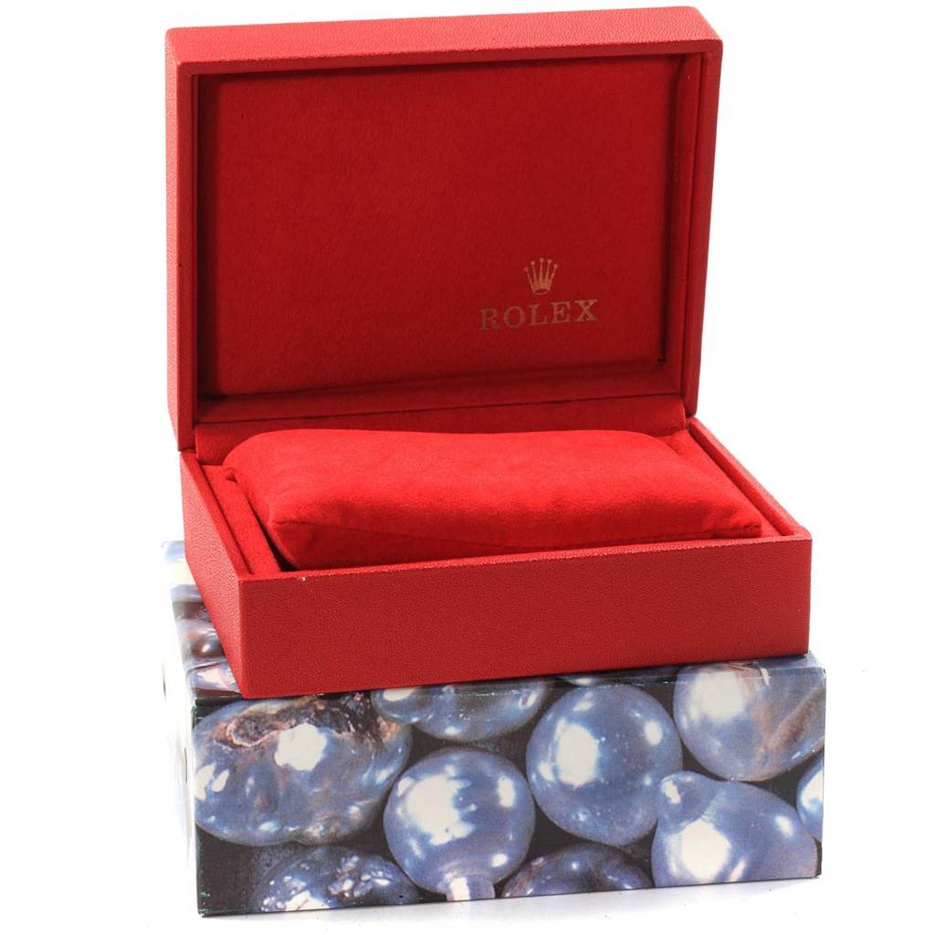 The image shows a red Rolex watch case and cushion for the Datejust model, set on a decorative box.