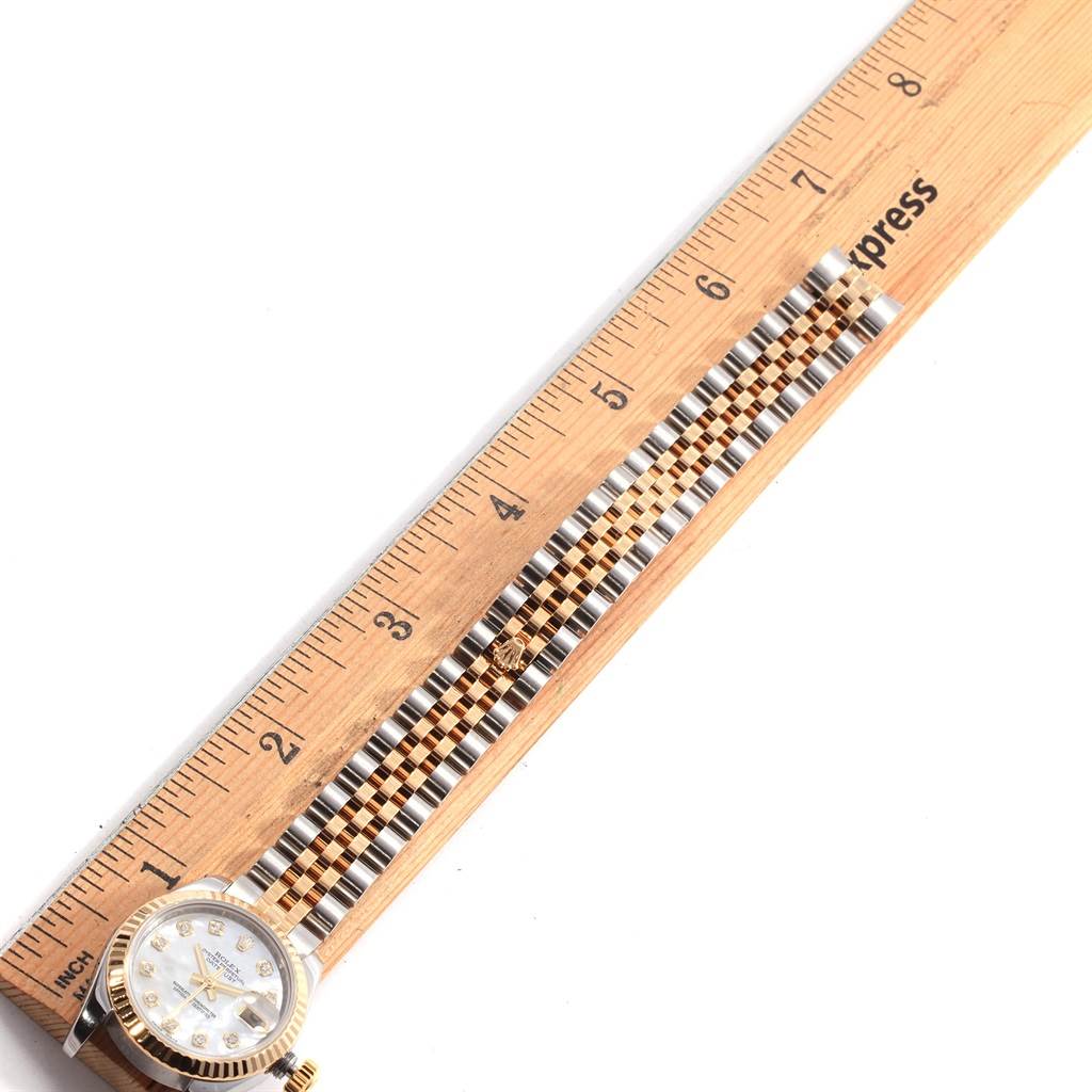 The Rolex Datejust 179173 Women's Steel and Gold (two tone) Mother of Pearl Dial 179173 Women's Steel and Gold (two tone) Mother of Pearl Dial watch is shown from the dial and bracelet perspective next to a ruler for measurement.