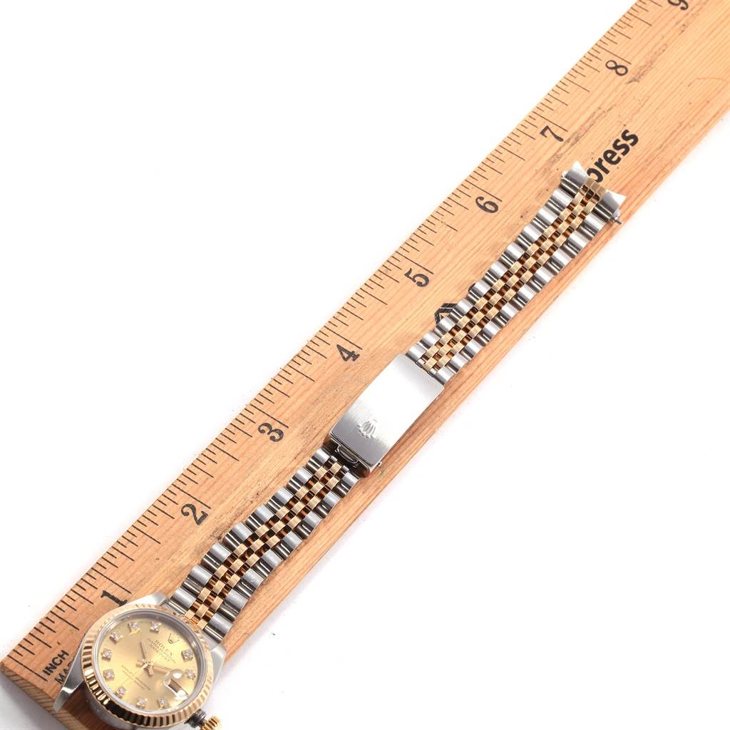 The image shows the Rolex Datejust 69173 Women
s Stainless Steel Champagne Dial 69173 Women
s Stainless Steel Champagne Dial watch with a jubilee bracelet laid flat next to a wooden ruler.