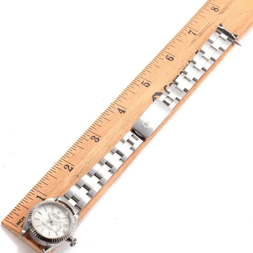 The image shows a top-down view of a Rolex Datejust 69174 Women's Stainless Steel Silver Dial 69174 Women's Stainless Steel Silver Dial watch alongside a wooden ruler for scale.