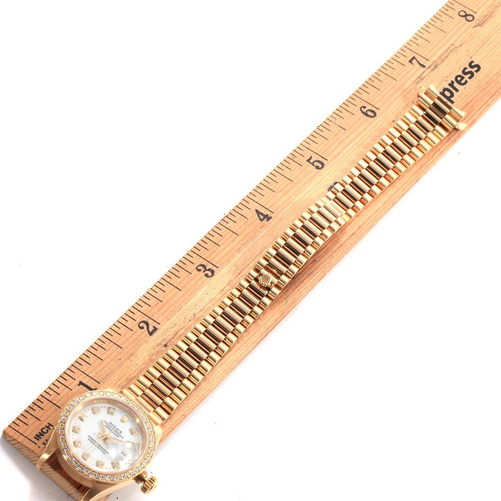 The image shows a top-down view of a Rolex Datejust 79178 Women's Yellow Gold White Dial 79178 Women's Yellow Gold White Dial watch, displaying its face, bezel, and bracelet laid next to a ruler.