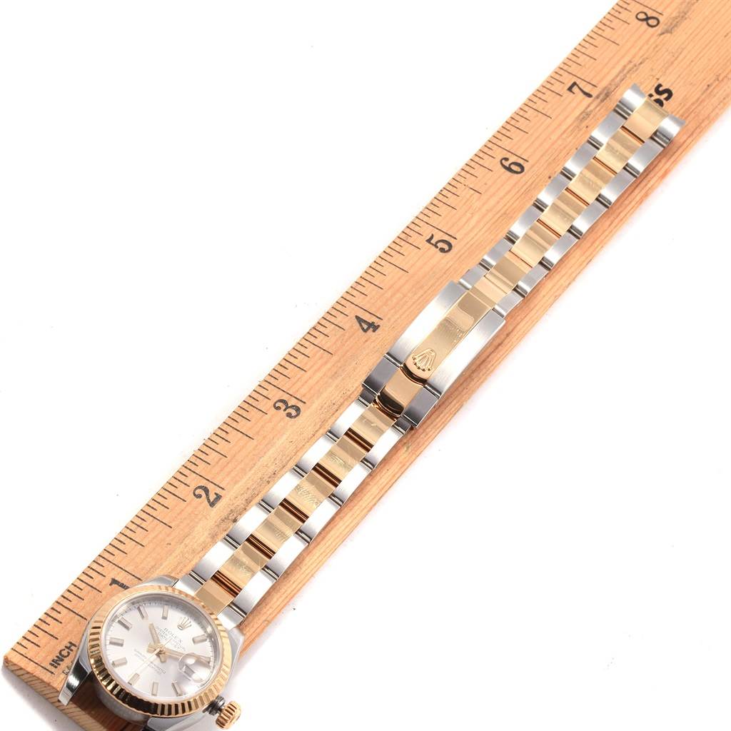 The image shows the Rolex Datejust 179173 Women's Steel and Gold (two tone) Silver Dial 179173 Women's Steel and Gold (two tone) Silver Dial watch placed next to a ruler, highlighting its face, bezel, and bracelet from a top-down view.