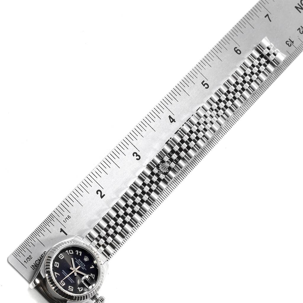 The image shows a Rolex Datejust 179174 Women
s Stainless Steel Black Dial 179174 Women
s Stainless Steel Black Dial watch with the face and part of the Jubilee bracelet measured against a metal ruler.