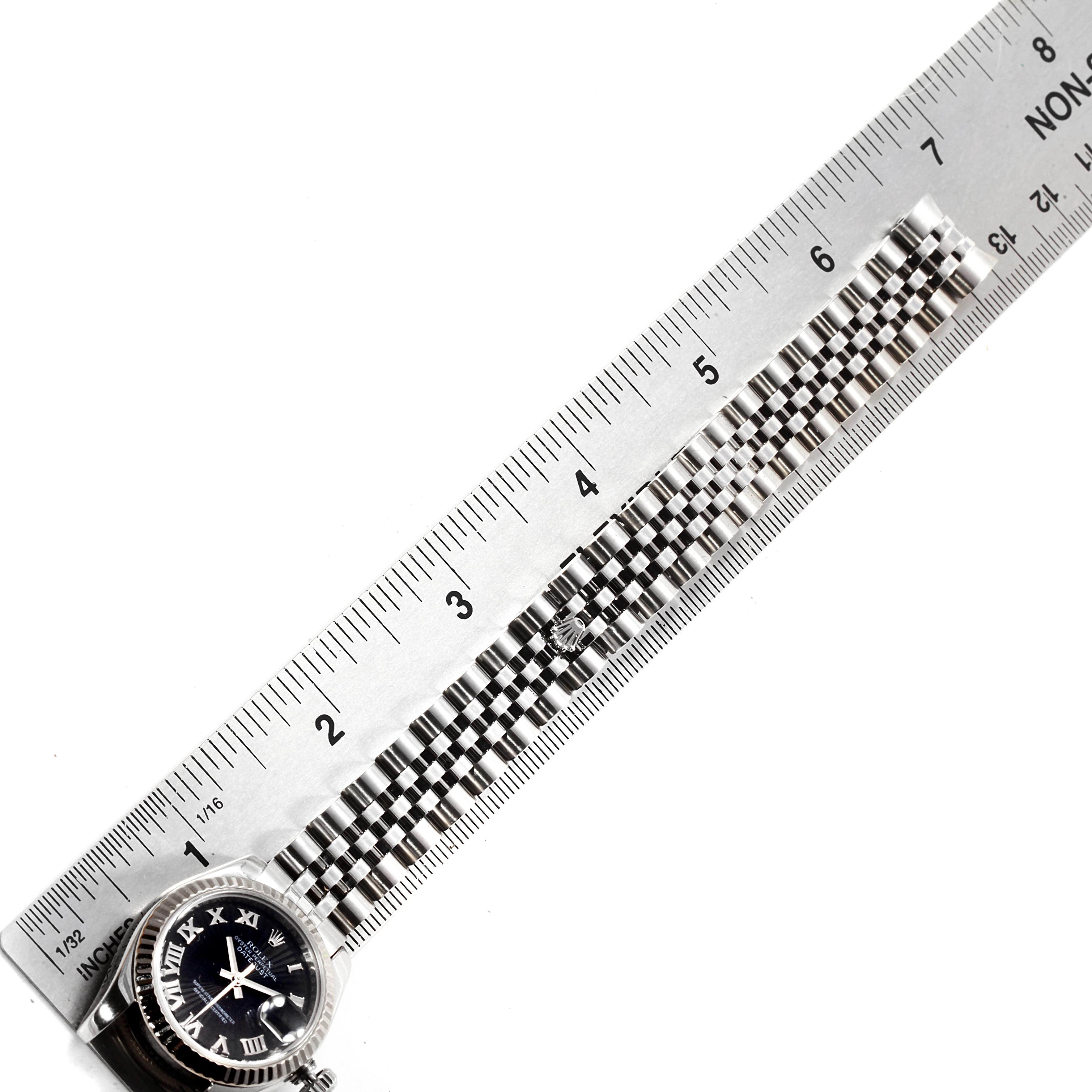 The image shows a Rolex Datejust 179174 Women's Stainless Steel Black Dial 179174 Women's Stainless Steel Black Dial watch face and part of its band, aligned beside a ruler for measurement.