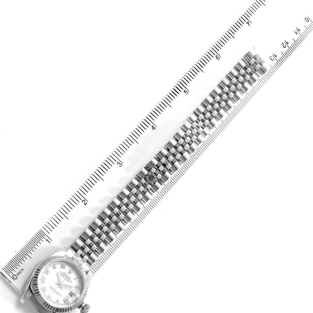 The image shows a Rolex Datejust 179174 Women
s Stainless Steel White Dial 179174 Women
s Stainless Steel White Dial watch placed next to a ruler, focusing on the face and bracelet from a top-down angle.
