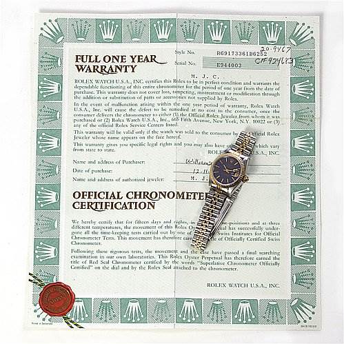 The image shows a Rolex Datejust 69173 Women's Stainless Steel Blue Dial 69173 Women's Stainless Steel Blue Dial watch placed diagonally over a warranty certificate.