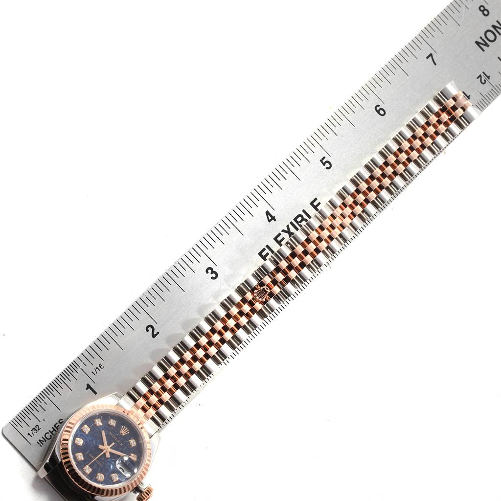 This image shows a Rolex Datejust 179171 Women
s Steel and Gold (two tone) Blue Dial 179171 Women
s Steel and Gold (two tone) Blue Dial watch laid flat with a close-up of its bracelet and face alongside a ruler for measurement.