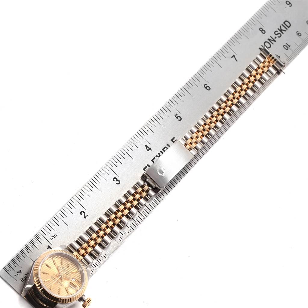 The image shows a Rolex Datejust 69173 Women
s Stainless Steel Champagne Dial 69173 Women
s Stainless Steel Champagne Dial watch face and partial band next to a measurement ruler.