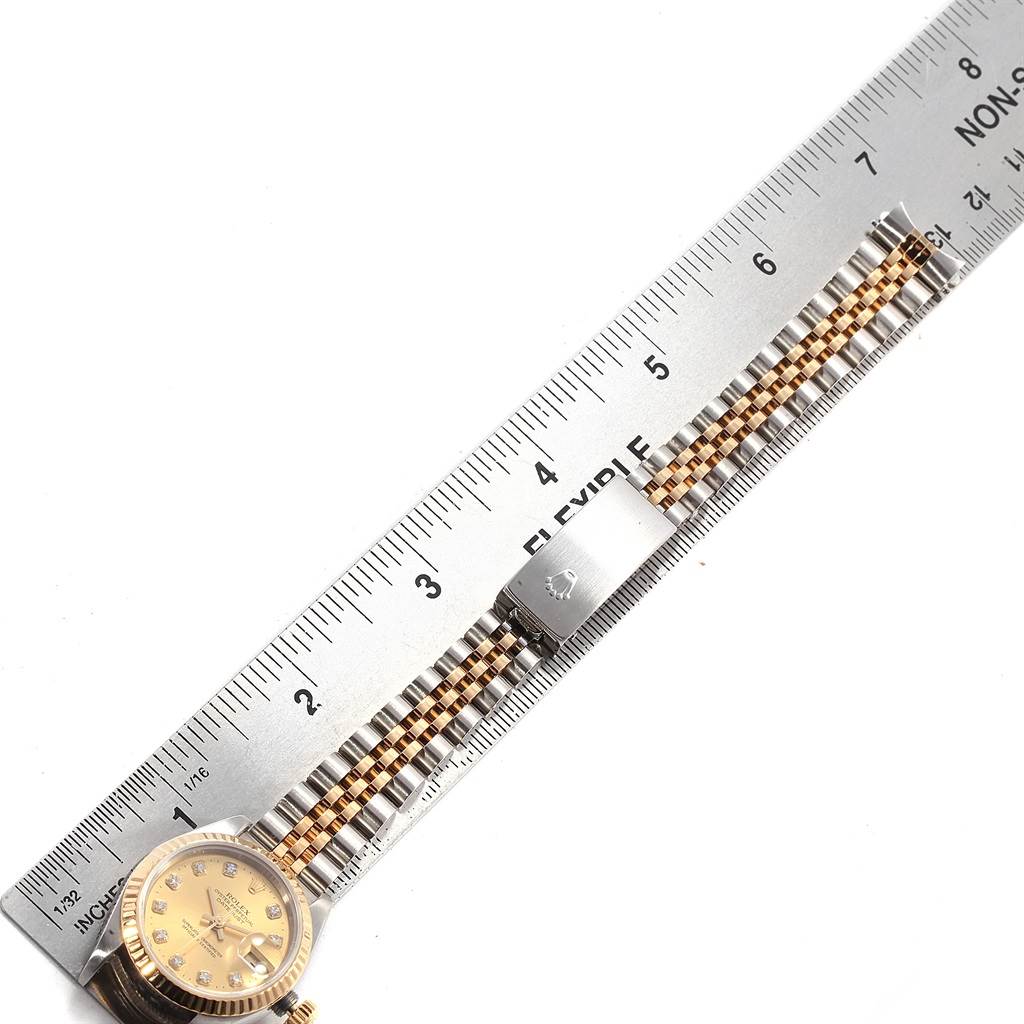The Rolex Datejust 69173 Women's Stainless Steel Champagne Dial 69173 Women's Stainless Steel Champagne Dial watch is shown from the top view, featuring its dial, bracelet, and clasp placed beside a ruler.