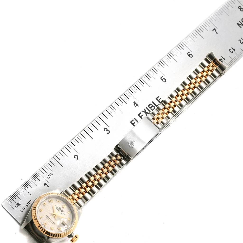 The Rolex Datejust 79173 Women's Steel and Gold (two tone) Beige Dial 79173 Women's Steel and Gold (two tone) Beige Dial watch is shown from above, featuring its face, bezel, and bracelet alongside a ruler for scale.