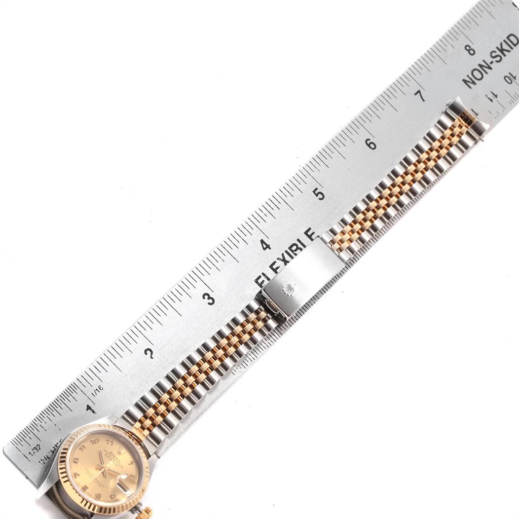 The image shows a Rolex Datejust 79173 Women's Steel and Gold (two tone) Champagne Dial 79173 Women's Steel and Gold (two tone) Champagne Dial watch laid flat next to a ruler, displaying the watchface and bracelet clasp.
