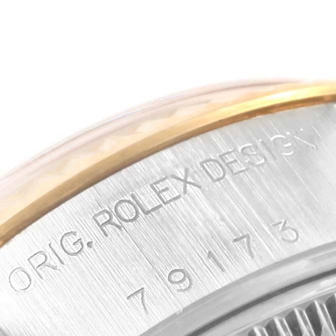 This close-up image shows the side of the Rolex Datejust 79173 Women's Steel and Gold (two tone) Champagne Dial 79173 Women's Steel and Gold (two tone) Champagne Dial watch, highlighting the engraved model number and part of the bezel.