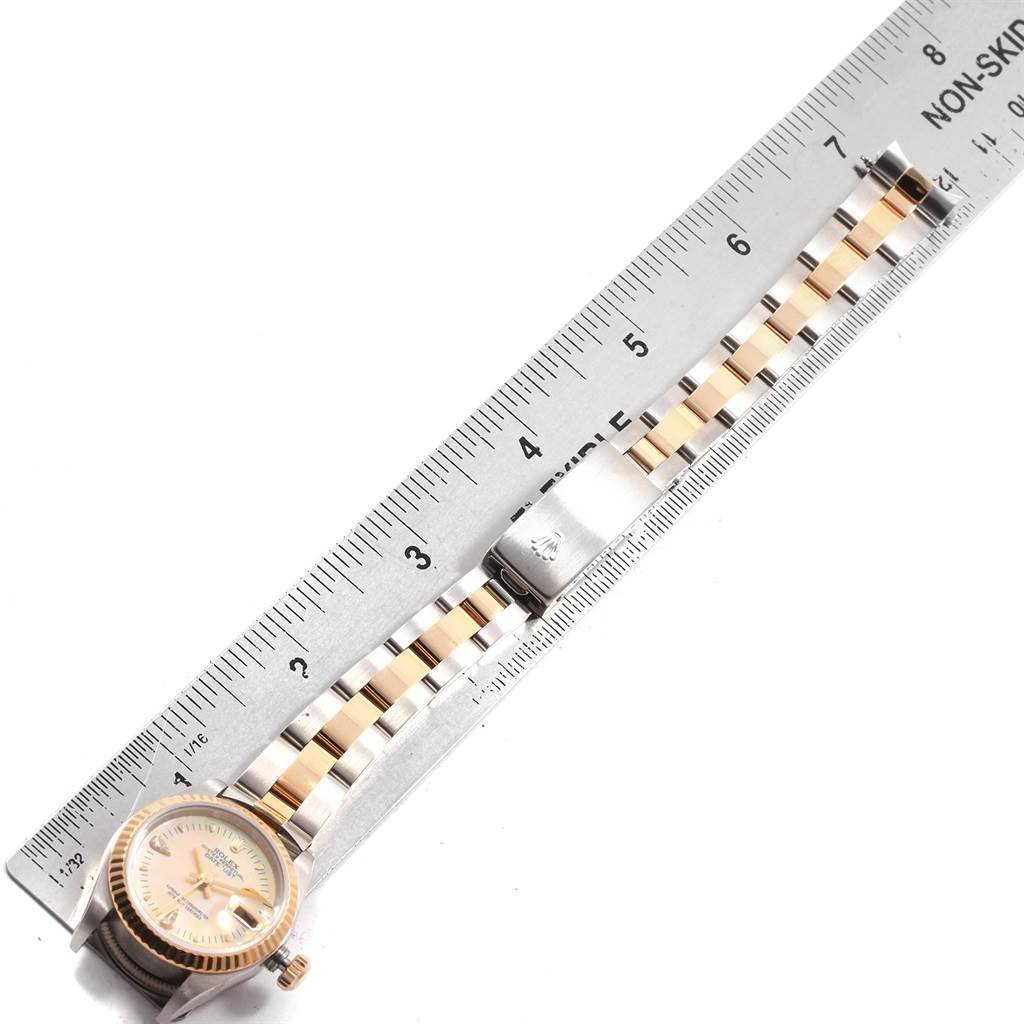 The Rolex Datejust 79173 Women's Stainless Steel Mother of Pearl Dial 79173 Women's Stainless Steel Mother of Pearl Dial watch is shown from the top view, displaying the face, bracelet, and clasp next to a ruler.