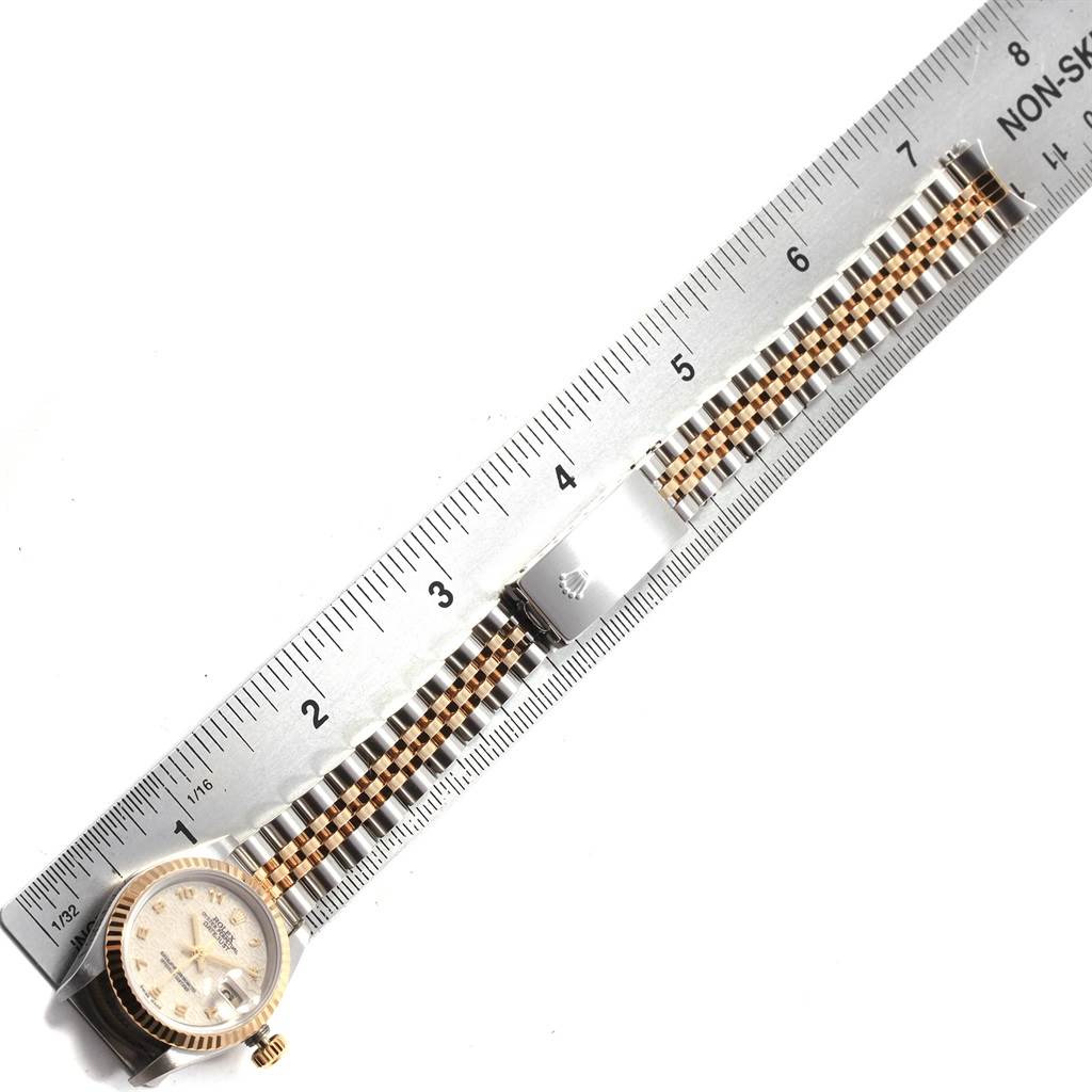 The Rolex Datejust 69173 Women's Stainless Steel Beige Dial 69173 Women's Stainless Steel Beige Dial watch is shown from a top-down angle with its case and bracelet alongside a ruler for measurement.