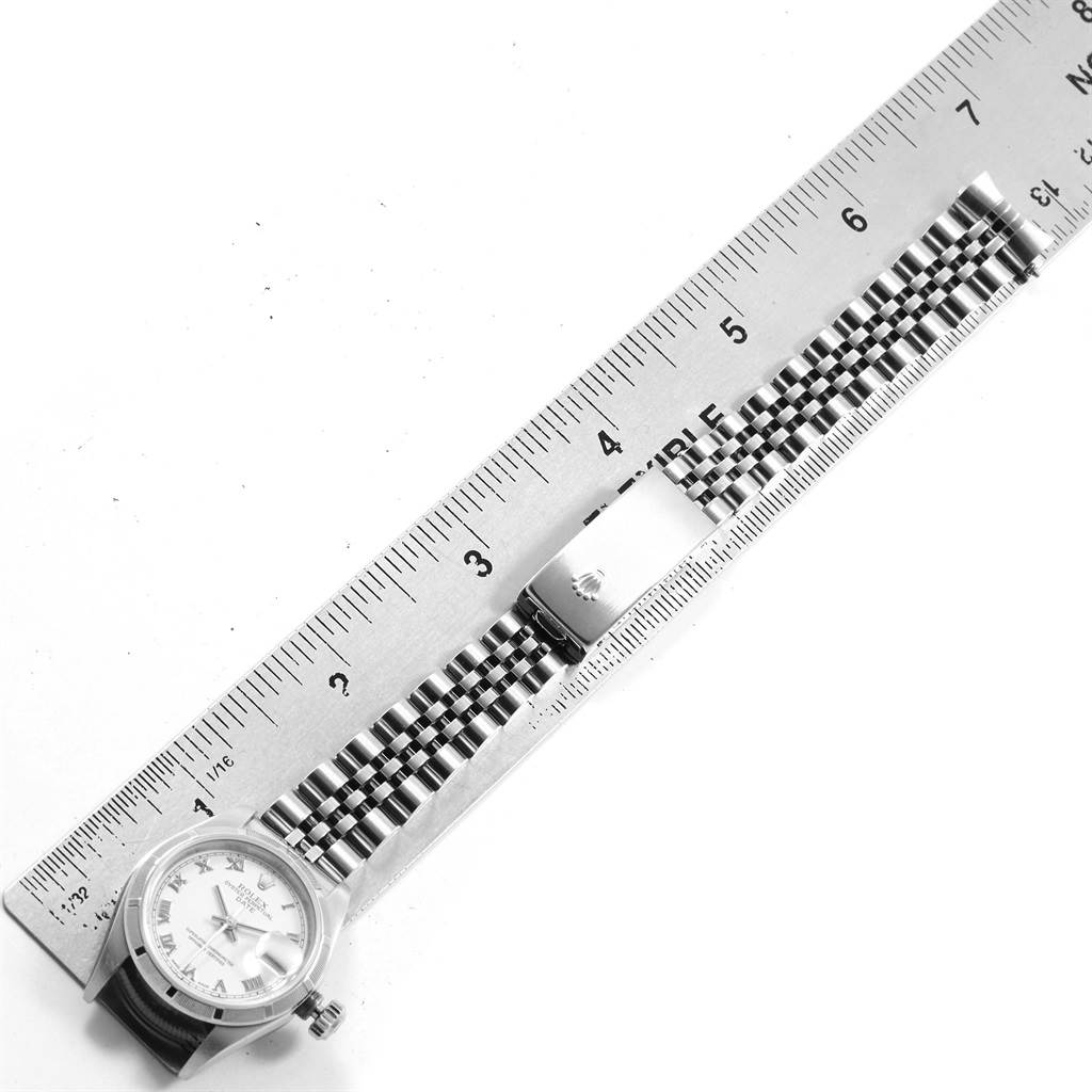 The image shows a Rolex Datejust 79190 Women
s Stainless Steel White Dial 79190 Women
s Stainless Steel White Dial watch and its Jubilee bracelet, positioned next to a ruler for measurement.