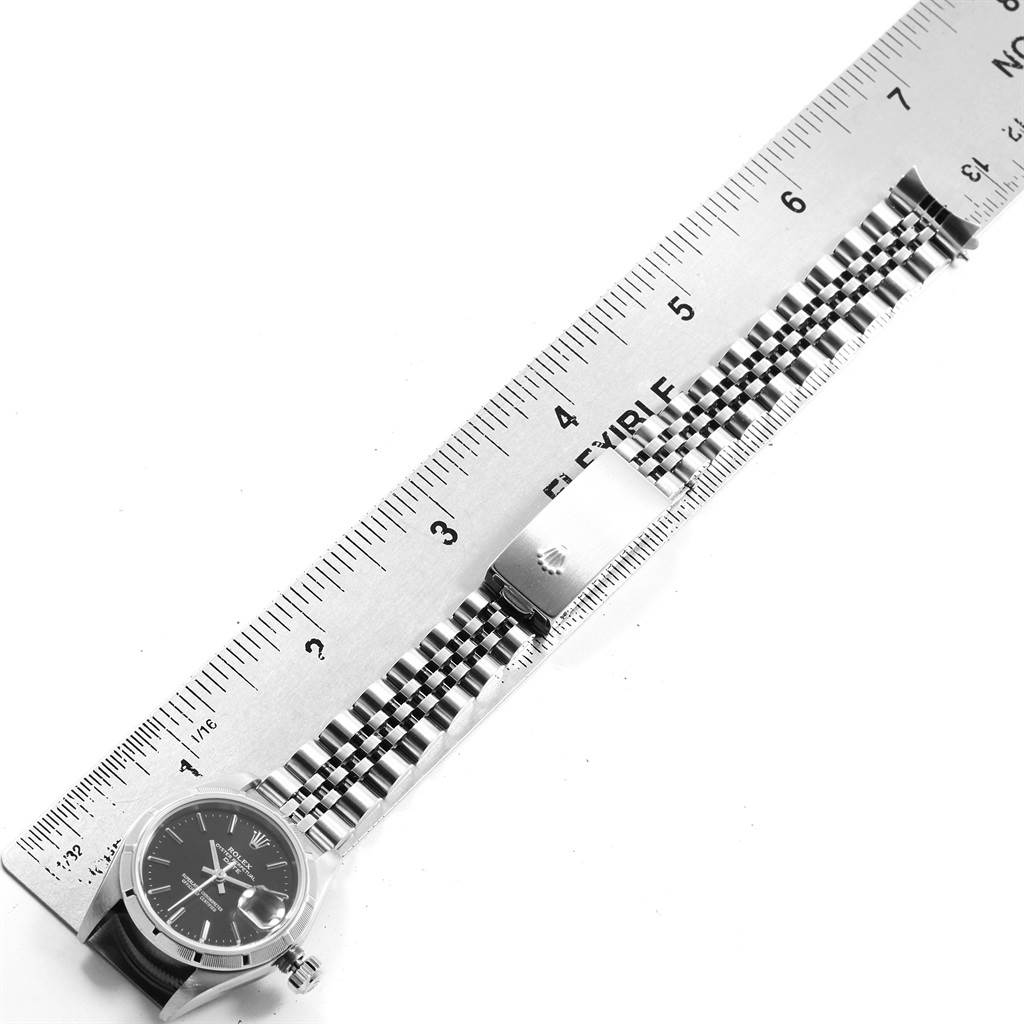 The image shows a top view of a Rolex Datejust 79190 Women's Stainless Steel Black Dial 79190 Women's Stainless Steel Black Dial watch's face, bracelet, and clasp placed alongside a ruler.