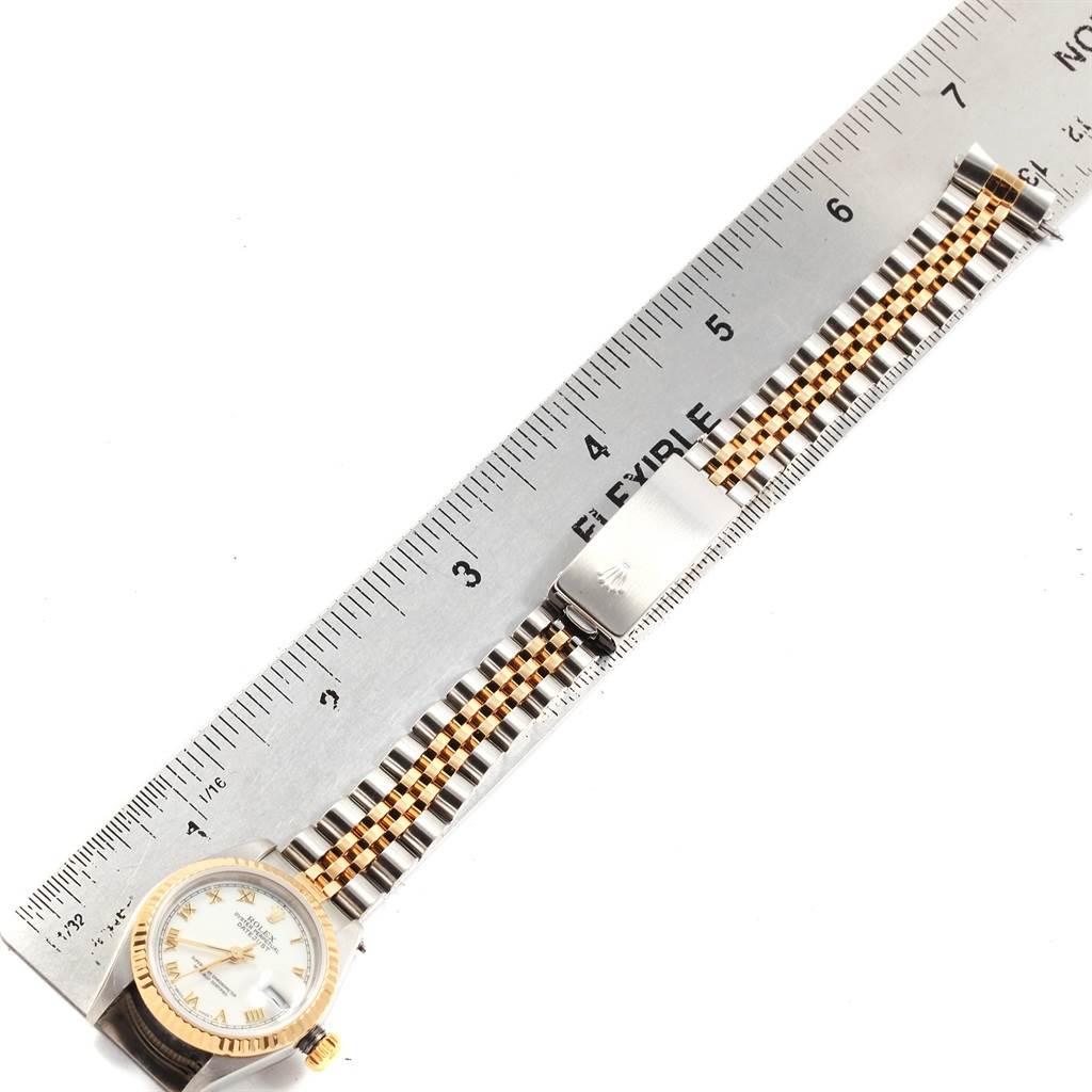 This is a top-view angle of a Rolex Datejust 19784 Women's Stainless Steel White Dial 19784 Women's Stainless Steel White Dial watch showing the dial, bezel, bracelet, and clasp, next to a ruler.
