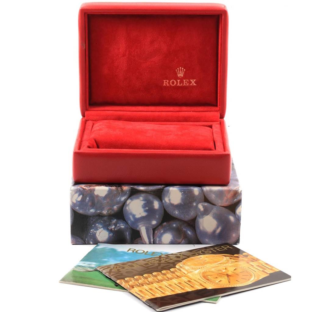 The image shows a Rolex Datejust 79174 Women
s Stainless Steel Pink Dial 79174 Women
s Stainless Steel Pink Dial model watch box with its lid open, resting on printed material including booklets.