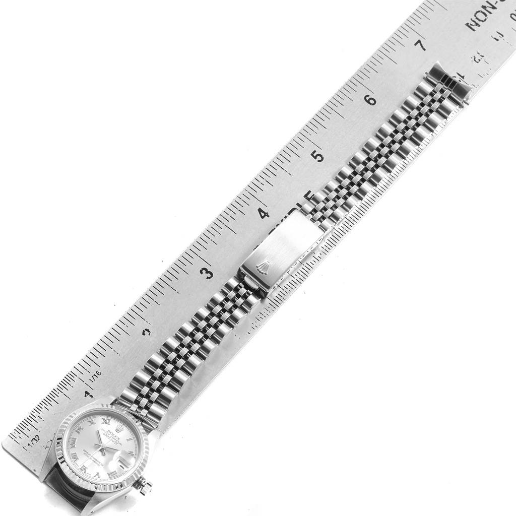 The Rolex Datejust 69174 Women's Stainless Steel Silver Dial 69174 Women's Stainless Steel Silver Dial watch is shown from above, displaying the face, bracelet, and clasp next to a ruler for scale.
