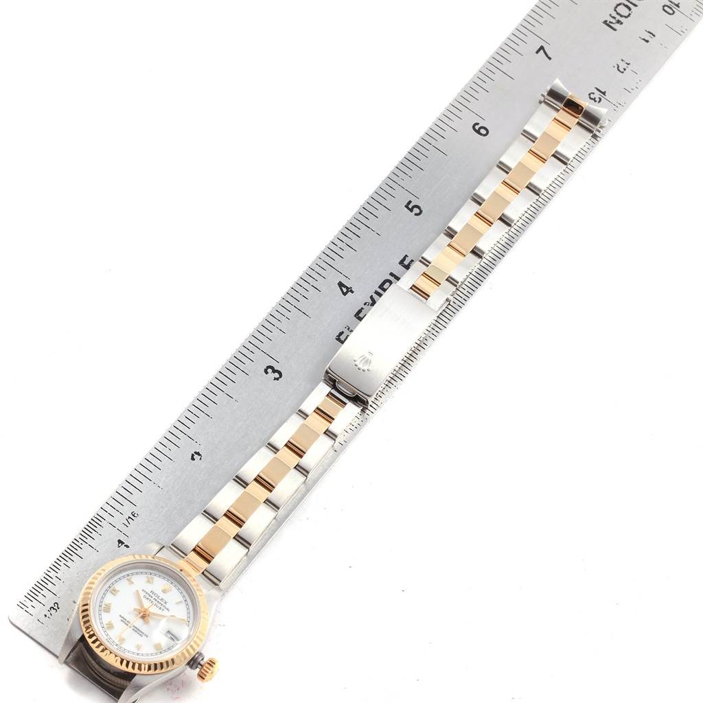 The Rolex Datejust 69173 Women's Stainless Steel White Dial 69173 Women's Stainless Steel White Dial watch is shown from an overhead angle, featuring its face, bezel, and two-tone bracelet beside a ruler.