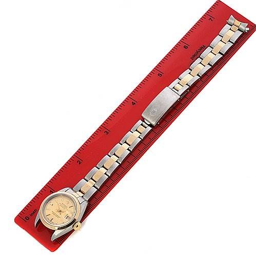The Rolex Datejust 69163 Women's Stainless Steel Champagne Dial 69163 Women's Stainless Steel Champagne Dial watch is shown from a top-down angle, with its full bracelet laid flat on a red ruler.