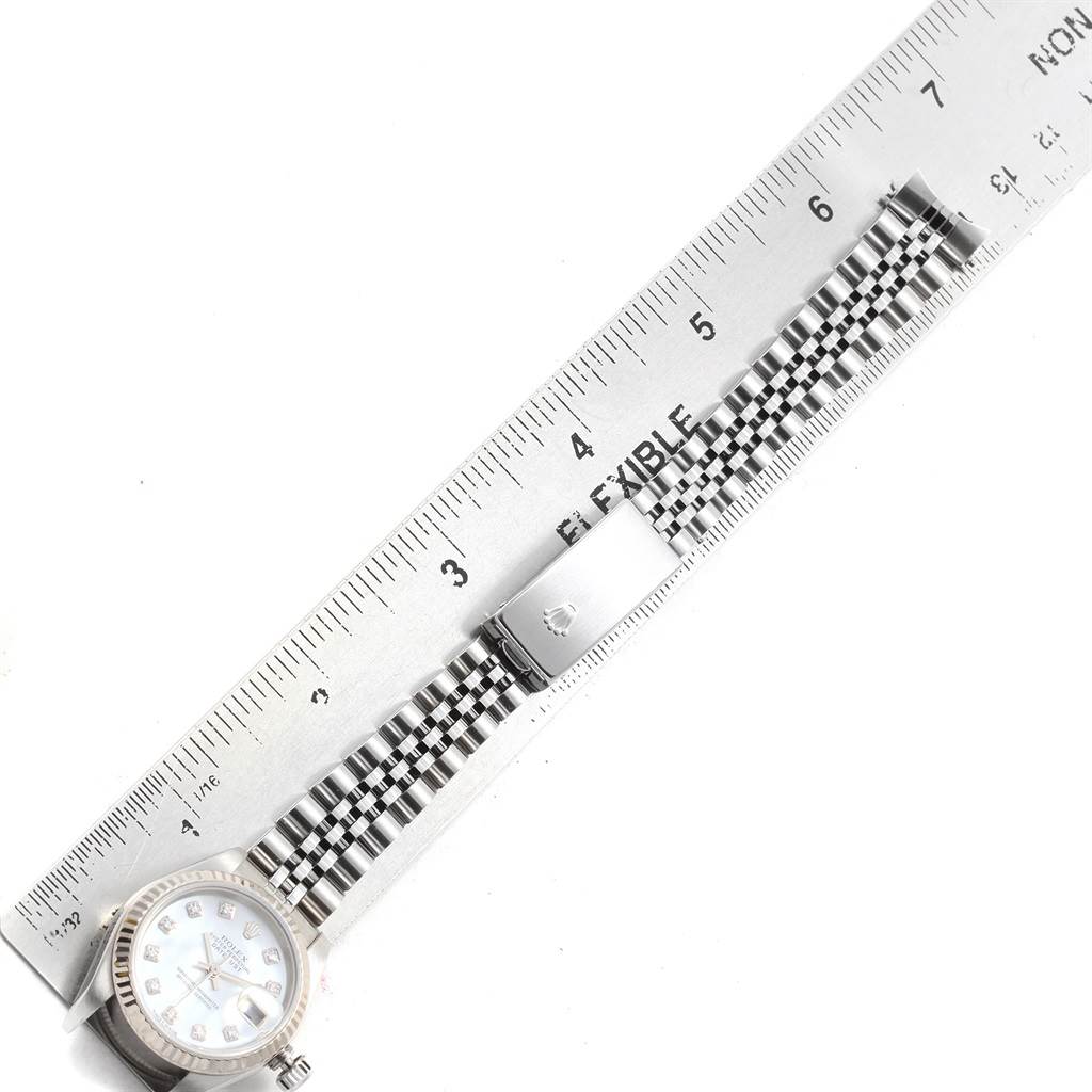 The image shows a Rolex Datejust 79174 Women
s Stainless Steel Mother of Pearl Dial 79174 Women
s Stainless Steel Mother of Pearl Dial watch with its bracelet extended alongside a ruler for measurement.