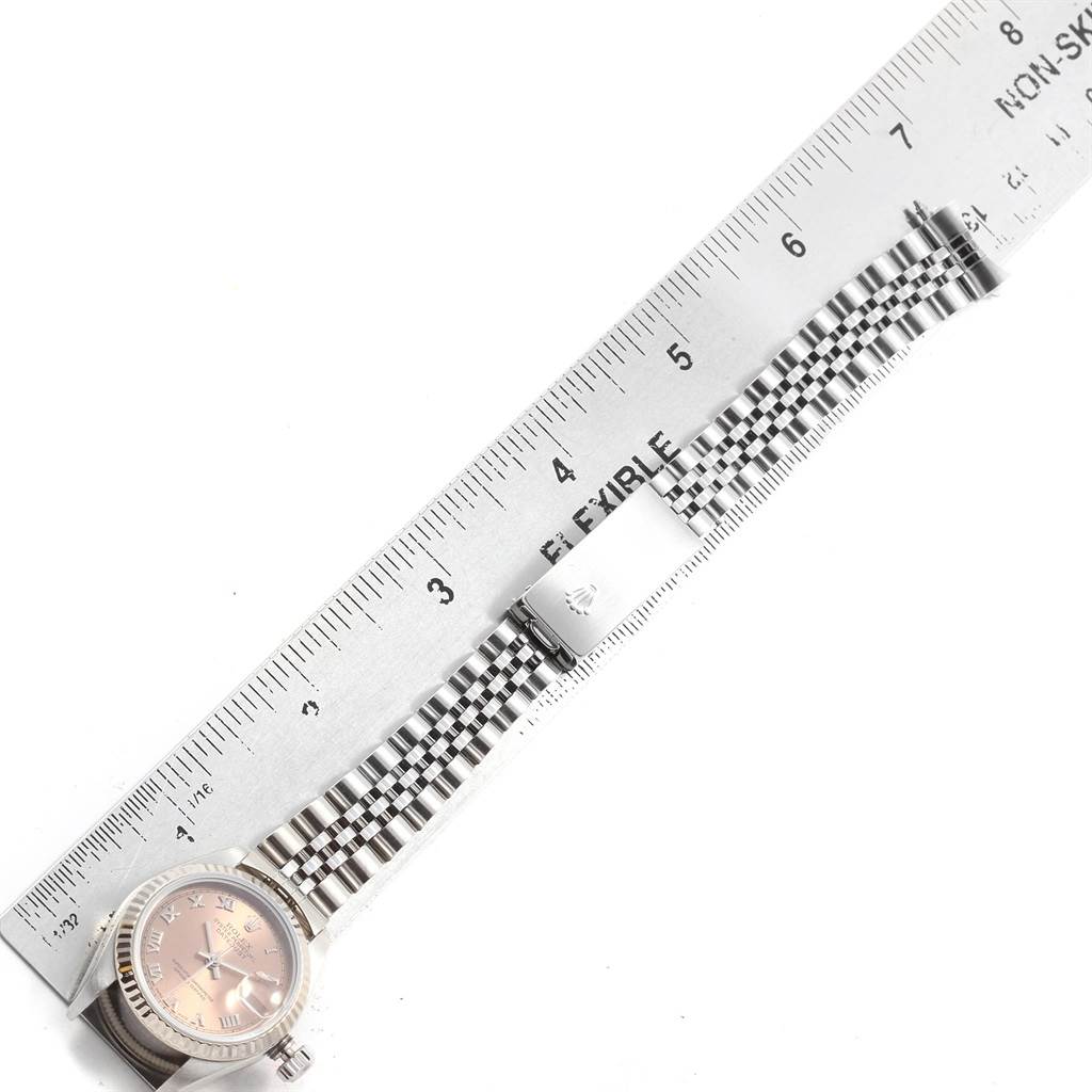 The image shows a top-down view of a Rolex Datejust 79174 Women's Stainless Steel Pink Dial 79174 Women's Stainless Steel Pink Dial watch with a focus on its face and bracelet, positioned next to a ruler.