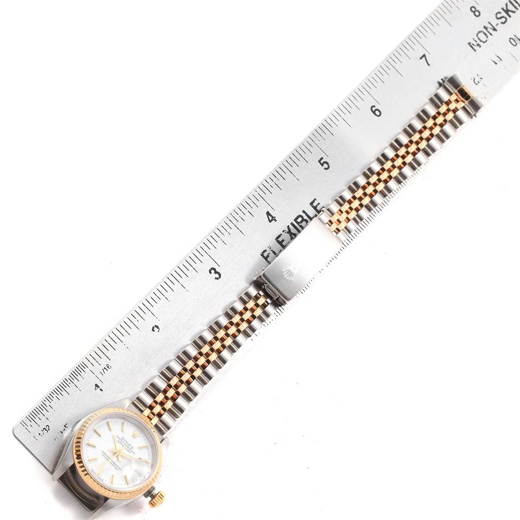 The Rolex Datejust 69173 Women
s Stainless Steel White Dial 69173 Women
s Stainless Steel White Dial watch is shown from above, next to a ruler, displaying its face and two-tone bracelet.