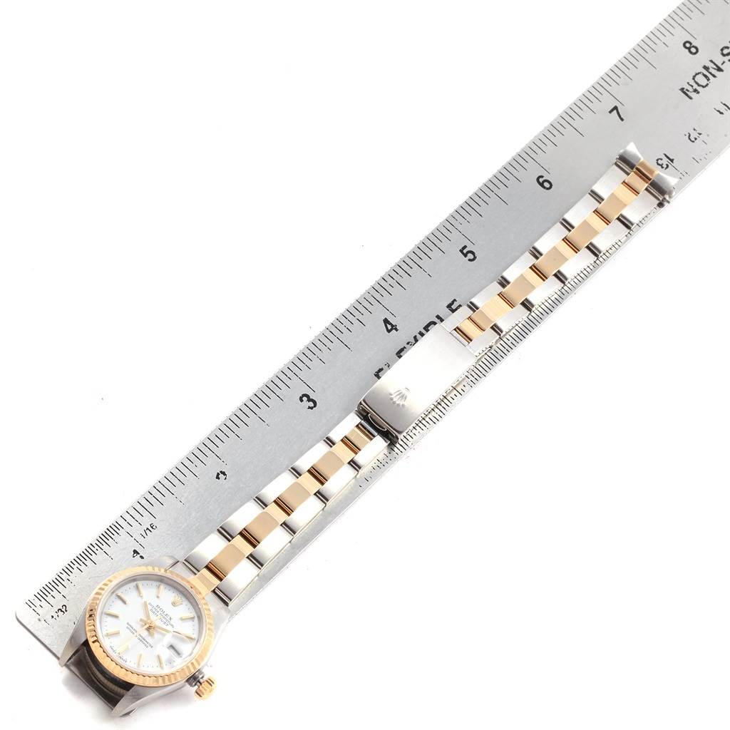 The image shows a Rolex Datejust 79173 Women's Steel and Gold (two tone) White Dial 79173 Women's Steel and Gold (two tone) White Dial watch laid flat with a metal bracelet and a ruler for size reference.