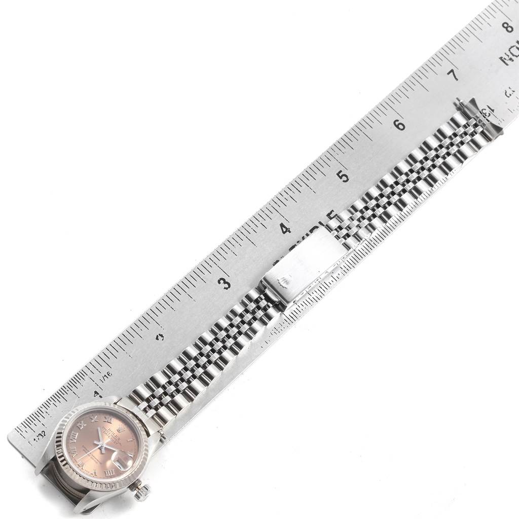 The image shows a side view of a Rolex Datejust 69174 Women
s Stainless Steel Pink Dial 69174 Women
s Stainless Steel Pink Dial watch with its bracelet next to a ruler for size reference.