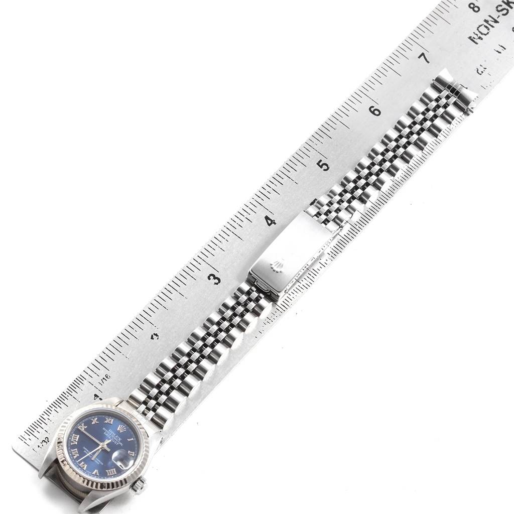 The image shows a Rolex Datejust 69174 Women
s Stainless Steel Blue Dial 69174 Women
s Stainless Steel Blue Dial watch laid flat next to a ruler, displaying the face and bracelet at an overhead angle.