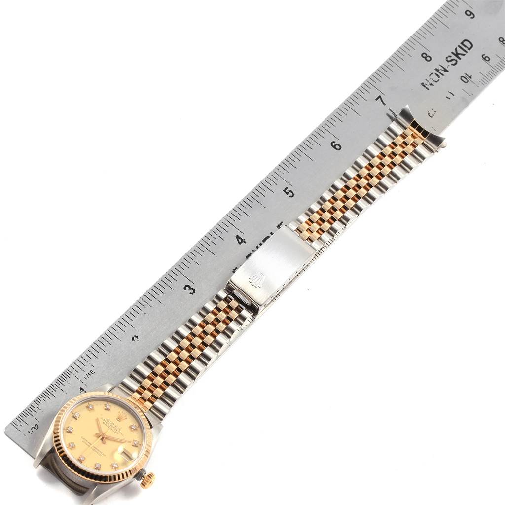 This image shows a Rolex Datejust 68273 Women's Steel and Gold (two tone) Champagne Dial 68273 Women's Steel and Gold (two tone) Champagne Dial watch laid flat, next to a ruler, displaying the watch face, bracelet, and clasp.