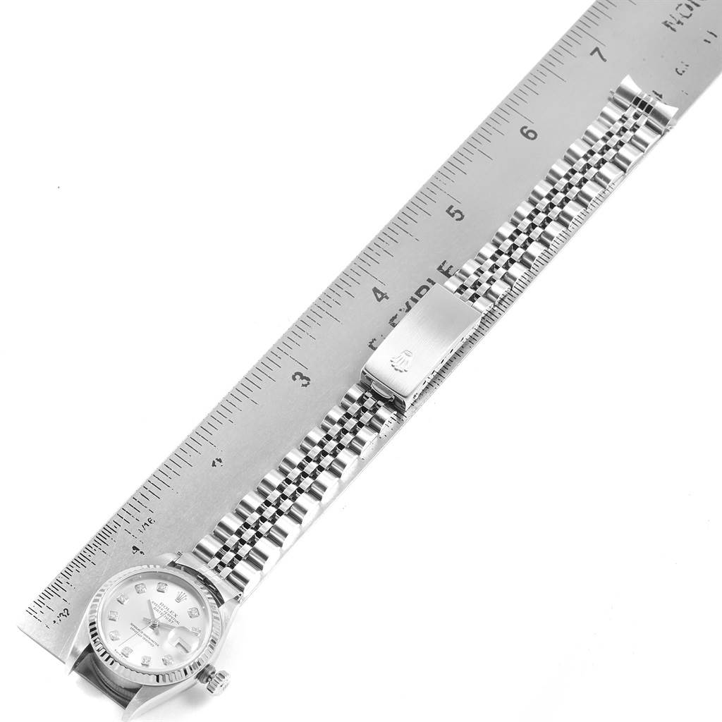 The image shows a top-down view of a Rolex Datejust 79174 Women
s Stainless Steel Silver Dial 79174 Women
s Stainless Steel Silver Dial watch, highlighting the face, crown, and Jubilee bracelet alongside a ruler.