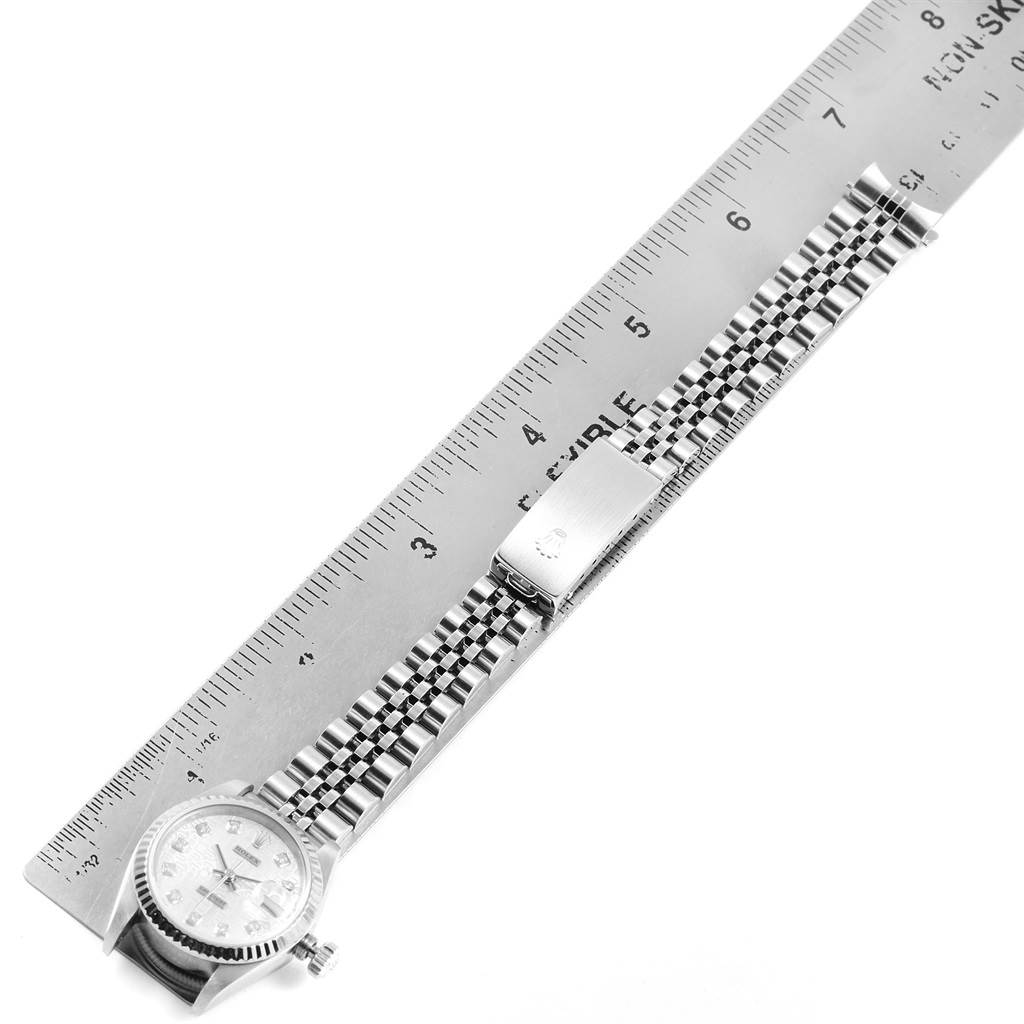 The Rolex Datejust 69174 Women
s Stainless Steel Silver Dial 69174 Women
s Stainless Steel Silver Dial watch is shown in a top-down angle, displaying the face, band, and clasp, alongside a ruler.