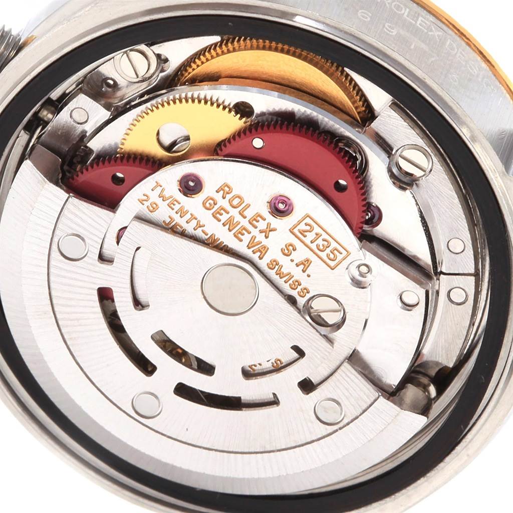 The image shows a close-up of the movement mechanism of a Rolex Datejust 69173 Women's Stainless Steel Blue Dial 69173 Women's Stainless Steel Blue Dial watch, highlighting the gears and internal components.