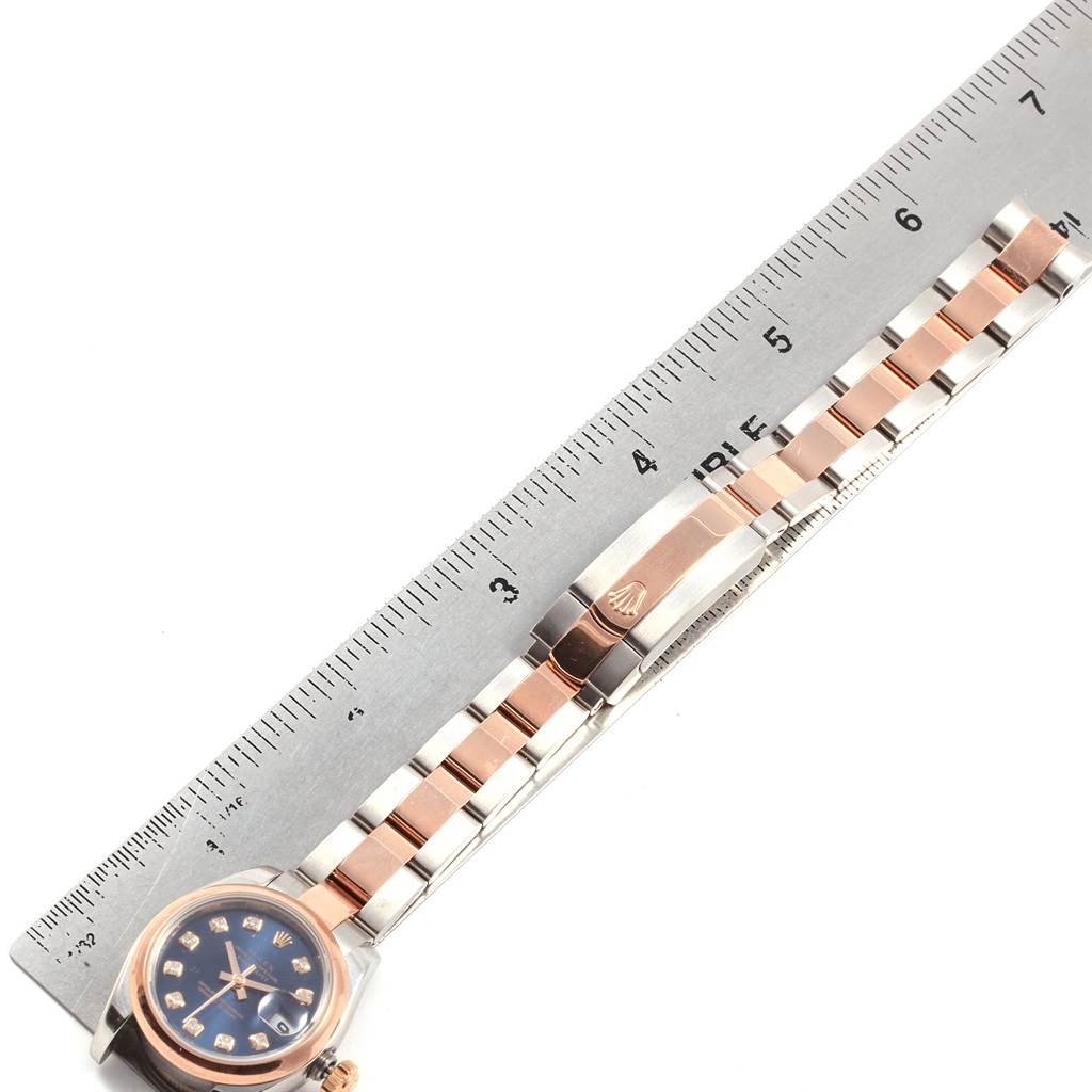 The image shows a top-down view of a Rolex Datejust 179161 Women's Steel and Gold (two tone) Blue Dial 179161 Women's Steel and Gold (two tone) Blue Dial watch alongside a ruler, displaying its bracelet and clasp.