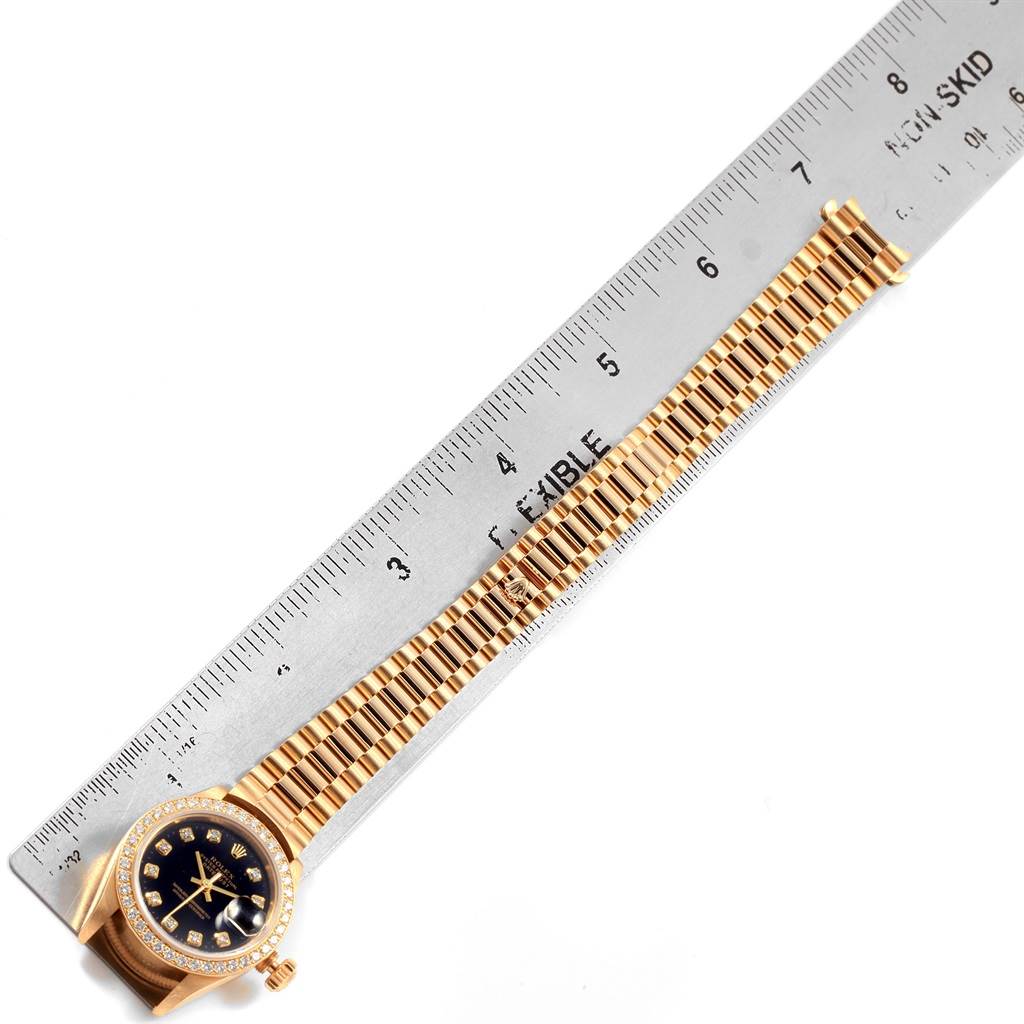 The image shows a gold Rolex Datejust 79138 Women's Yellow Gold Black Dial 79138 Women's Yellow Gold Black Dial watch with its band and a ruler for scale from a top-down angle.