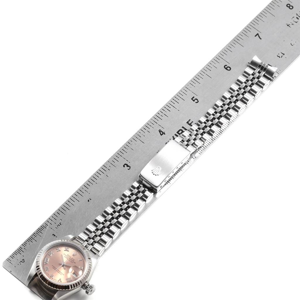 The image shows a side angle of a Rolex Datejust 79174 Women's Stainless Steel Pink Dial 79174 Women's Stainless Steel Pink Dial watch placed next to a ruler, highlighting the watch face and jubilee bracelet with clasp.