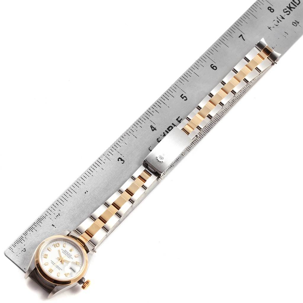 The image shows a top-down view of a Rolex Datejust 79163 Women's Steel and Gold (two tone) White Dial 79163 Women's Steel and Gold (two tone) White Dial watch face and its full bracelet next to a ruler.
