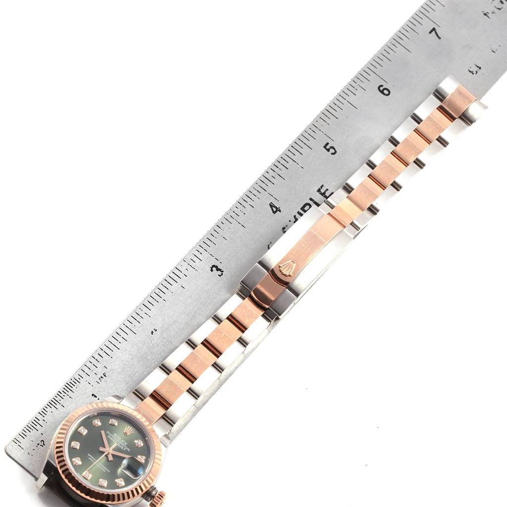 This image shows a Rolex Datejust 279171 Women's Steel and Gold (two tone) Green Dial 279171 Women's Steel and Gold (two tone) Green Dial watch laid next to a ruler, displaying both the face and the two-tone bracelet.