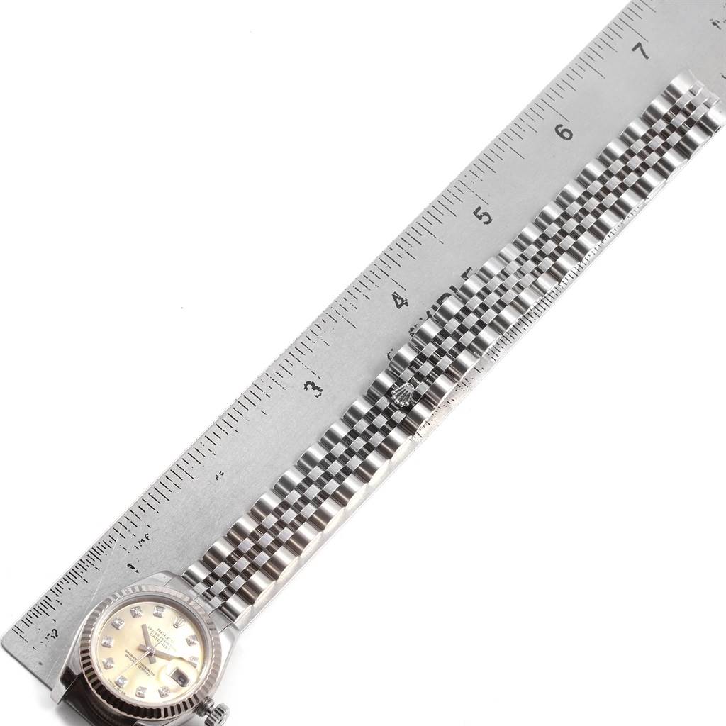 The image shows a Rolex Datejust 179174 Women
s Stainless Steel Mother of Pearl Dial 179174 Women
s Stainless Steel Mother of Pearl Dial watch aligned with a ruler, focusing on its bracelet and face.