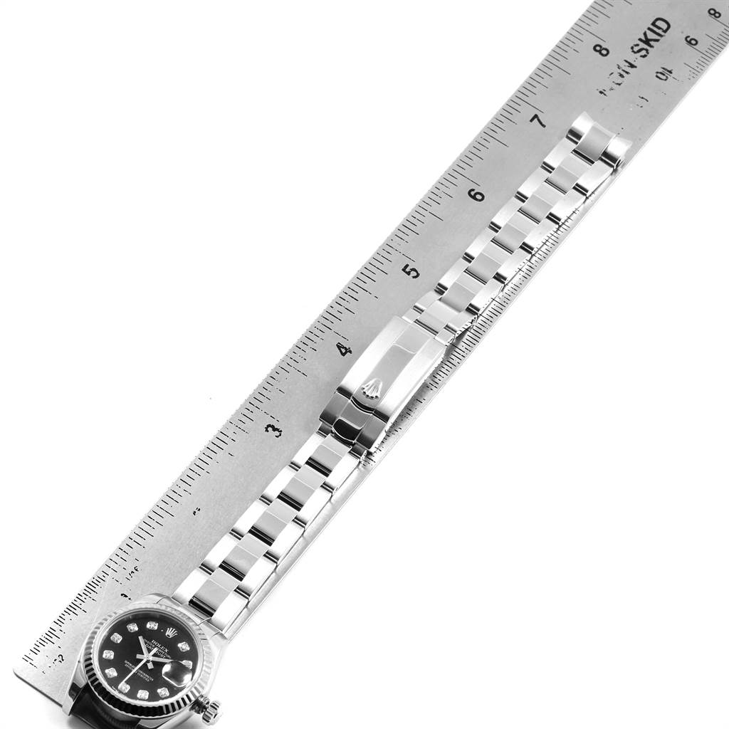 The image shows a Rolex Datejust 179174 Women
s Stainless Steel Black Dial 179174 Women
s Stainless Steel Black Dial watch placed next to a ruler, displaying its face, bracelet, and clasp.