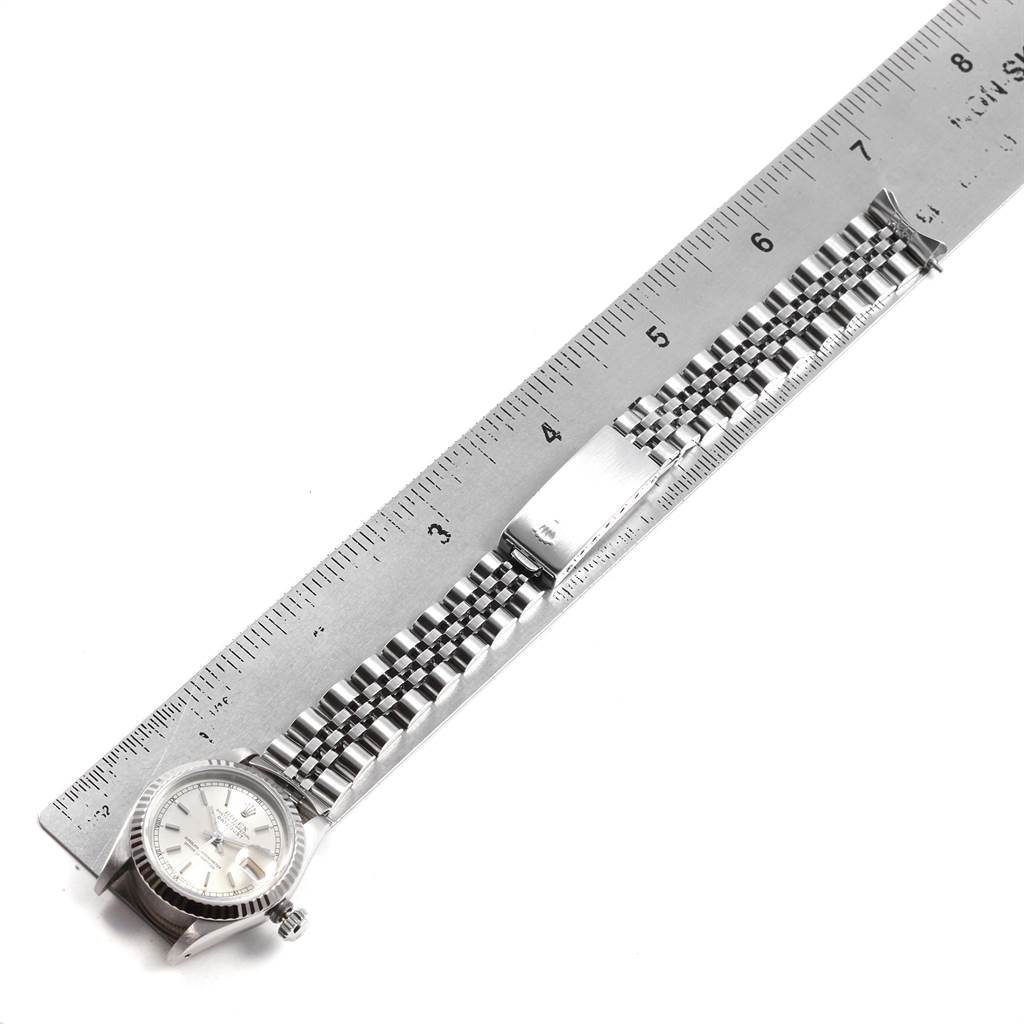 The image shows a top-down view of a Rolex Datejust 69174 Women
s Stainless Steel Silver Dial 69174 Women
s Stainless Steel Silver Dial watch and its metal bracelet next to a ruler.