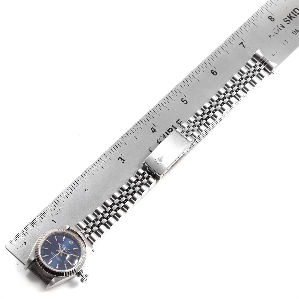 The image shows a Rolex Datejust 69174 Women
s Stainless Steel Blue Dial 69174 Women
s Stainless Steel Blue Dial watch laid flat alongside a ruler, displaying its entire bracelet and clasp.