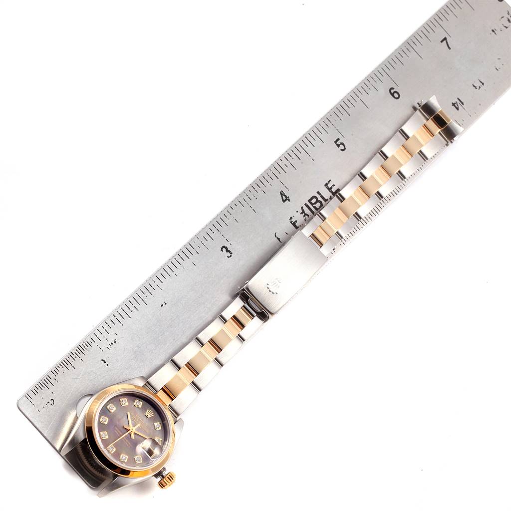 The image shows an overhead view of a Rolex Datejust 79163 Women's Steel and Gold (two tone) Mother of Pearl Dial 79163 Women's Steel and Gold (two tone) Mother of Pearl Dial watch, including its face, bracelet, and a ruler beside it for scale.