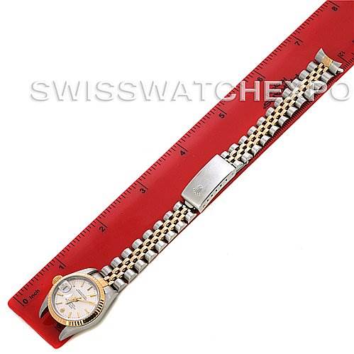 The image shows a top view of a Rolex Datejust 79173 Women
s Stainless Steel Silver Dial 79173 Women
s Stainless Steel Silver Dial watch, including the face, case, and bracelet, alongside a red ruler for scale.