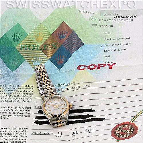The image shows a Rolex Datejust 79173 Women
s Stainless Steel Silver Dial 79173 Women
s Stainless Steel Silver Dial watch, featuring a full view of the timepiece and its bracelet, placed on top of its certificate.