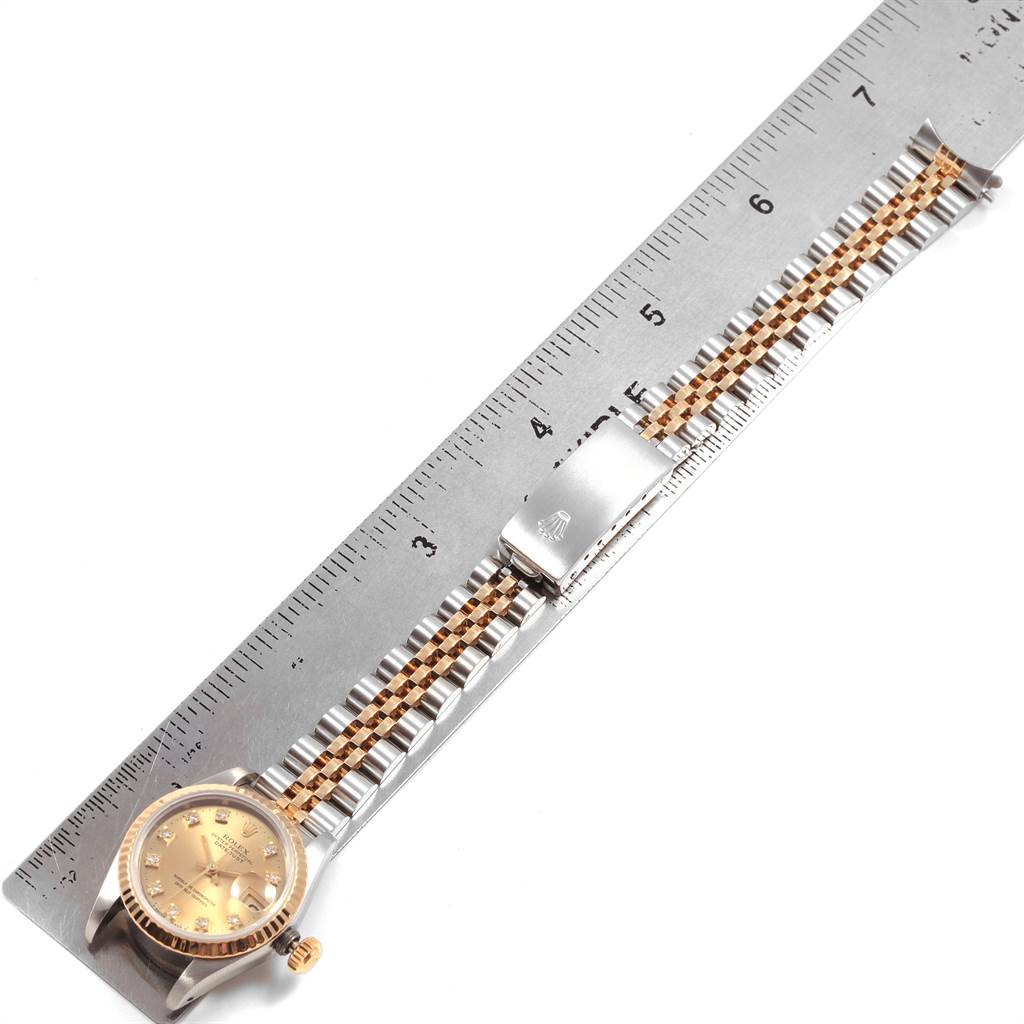 The Rolex Datejust 69173 Women's Stainless Steel Champagne Dial 69173 Women's Stainless Steel Champagne Dial watch is shown flat with its face, bracelet, and clasp visible next to a ruler for scale.