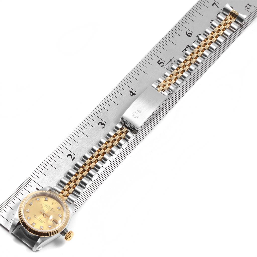 This image shows a Rolex Datejust 69173 Women's Stainless Steel Champagne Dial 69173 Women's Stainless Steel Champagne Dial model watch laid flat against a ruler, emphasizing its bracelet and clasp.